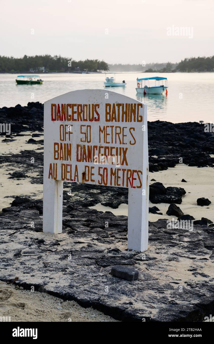 Gefahrenwarnschild am Blue Bay Beach auf Mauritius Island mit Booten Stockfoto