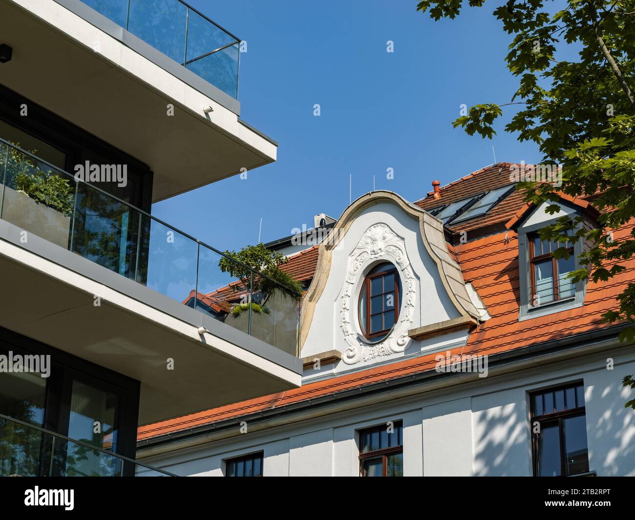 Moderne und alte Gebäudefassade nebeneinander. Luxuriöser Balkon mit Glasgeländern und Pflanzen. Unterschiedliche Wohnarchitektur in Deutschland. Stockfoto