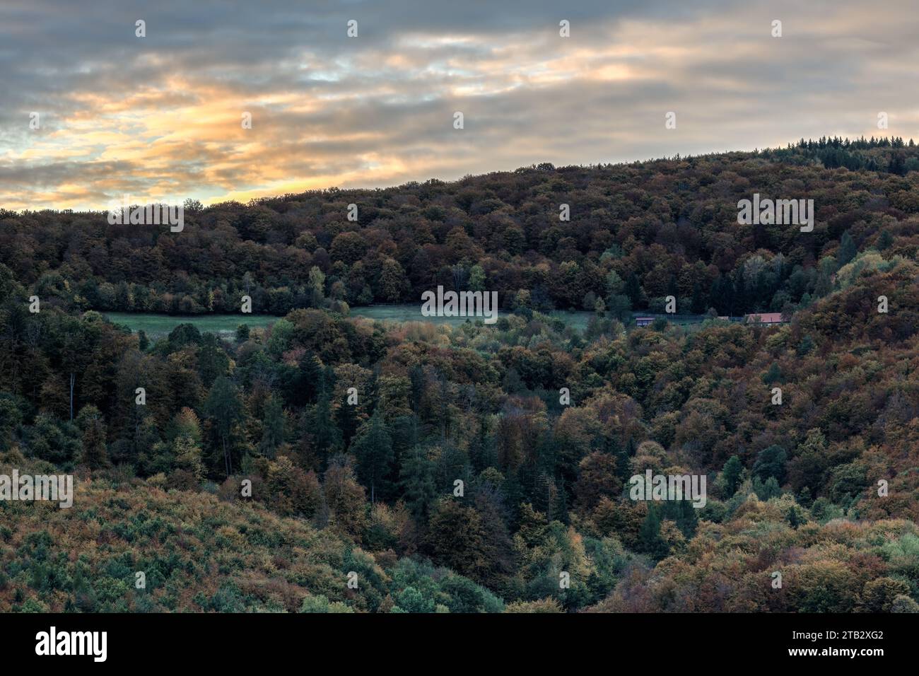 Herbstliche Berglandschaft mit Wald und wunderschönem farbenfrohen Himmel bei Sonnenuntergang. Mit einem einsamen Haus. Horna Suca, Dubrava Slowakei Stockfoto