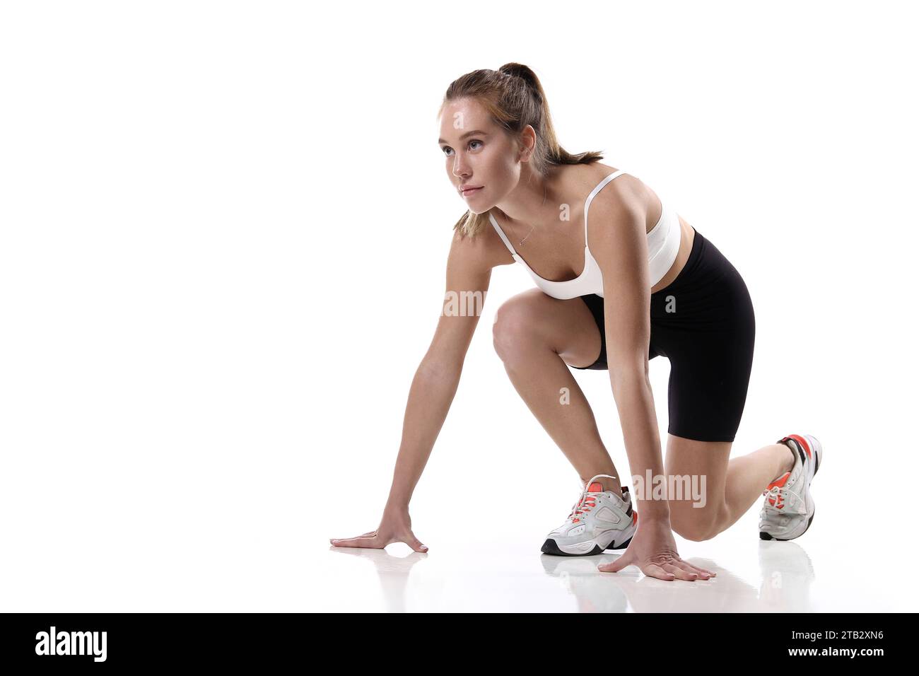 Attraktiv sitzende Frau, die im Studio mit Copyspace trainiert. Bild einer gesunden jungen Athletin, die Fitness-Workout vor weißem Hintergrund macht. Stockfoto