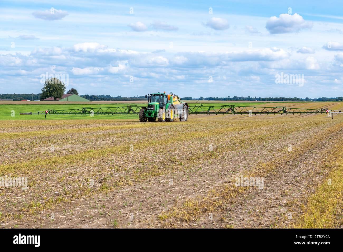 Spurenelemente auf einem neu gesäten Rapsfeld ausbreiten. John Deere 6620 Traktor und gezogene Feldspritze Amazone UX 4201 Stockfoto