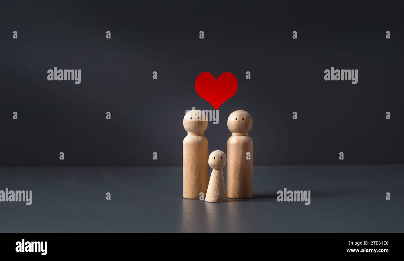 Familie von Holzfiguren auf graublauem Hintergrund mit rotem Herz, Konzept des Familienlebens, Familienplanung und Lebenshaltungskosten. Stockfoto
