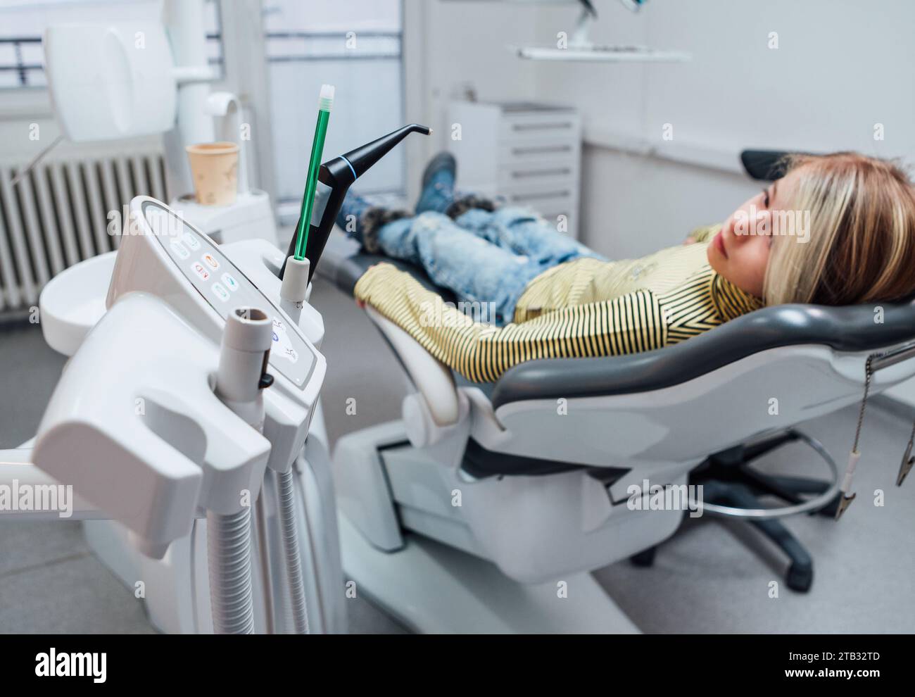 Medizinischer Stuhl Vakuuminstrumente Foto. Kleines Mädchen, das nach zahnärztlichen Eingriffen auf dem Stomatologie-Klinikstuhl sitzt. Gesundheitswesen, Kindergesundheit Stockfoto