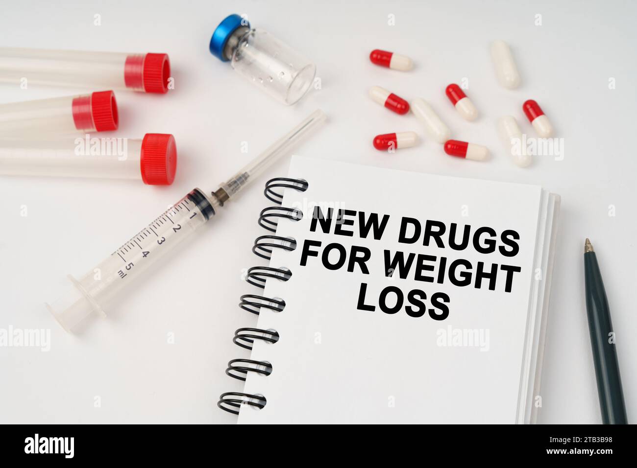 Medizinisches Konzept. Auf dem Tisch stehen Pillen, Injektionen, eine Spritze und ein Notizblock mit der Aufschrift - neue Medikamente zur Gewichtsreduktion Stockfoto