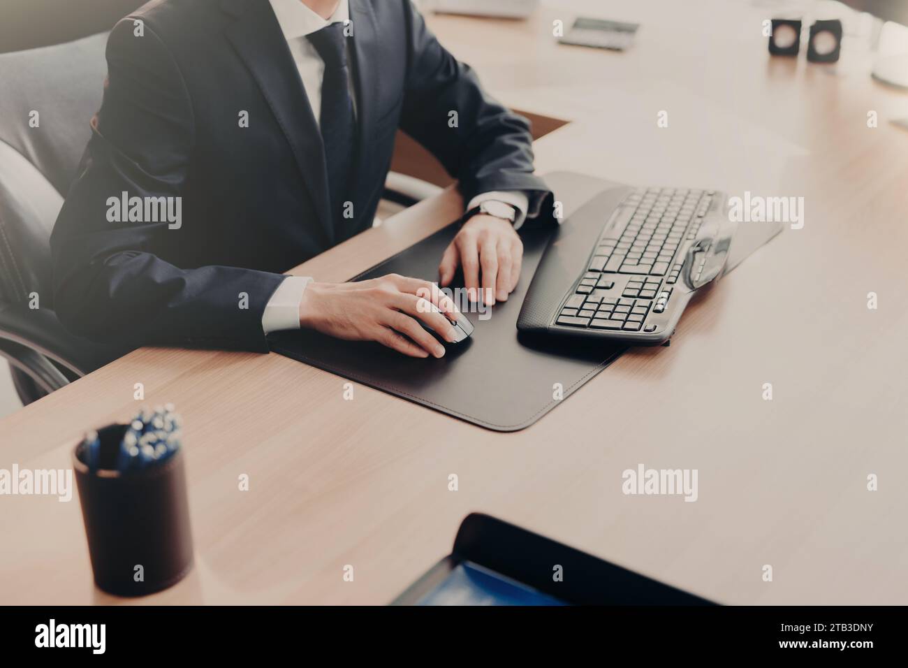Ein fokussierter Geschäftsmann, der den Computer an einem schlanken Schreibtisch verwendet Stockfoto