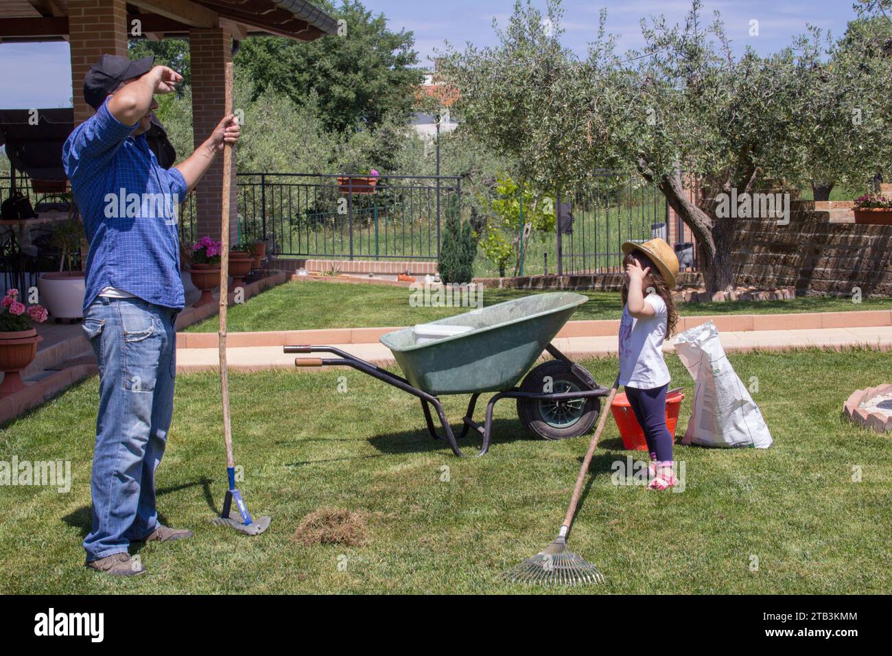 Bild eines müden jungen Vaters, während er und seine kleine Tochter Gartenarbeiten machen Stockfoto
