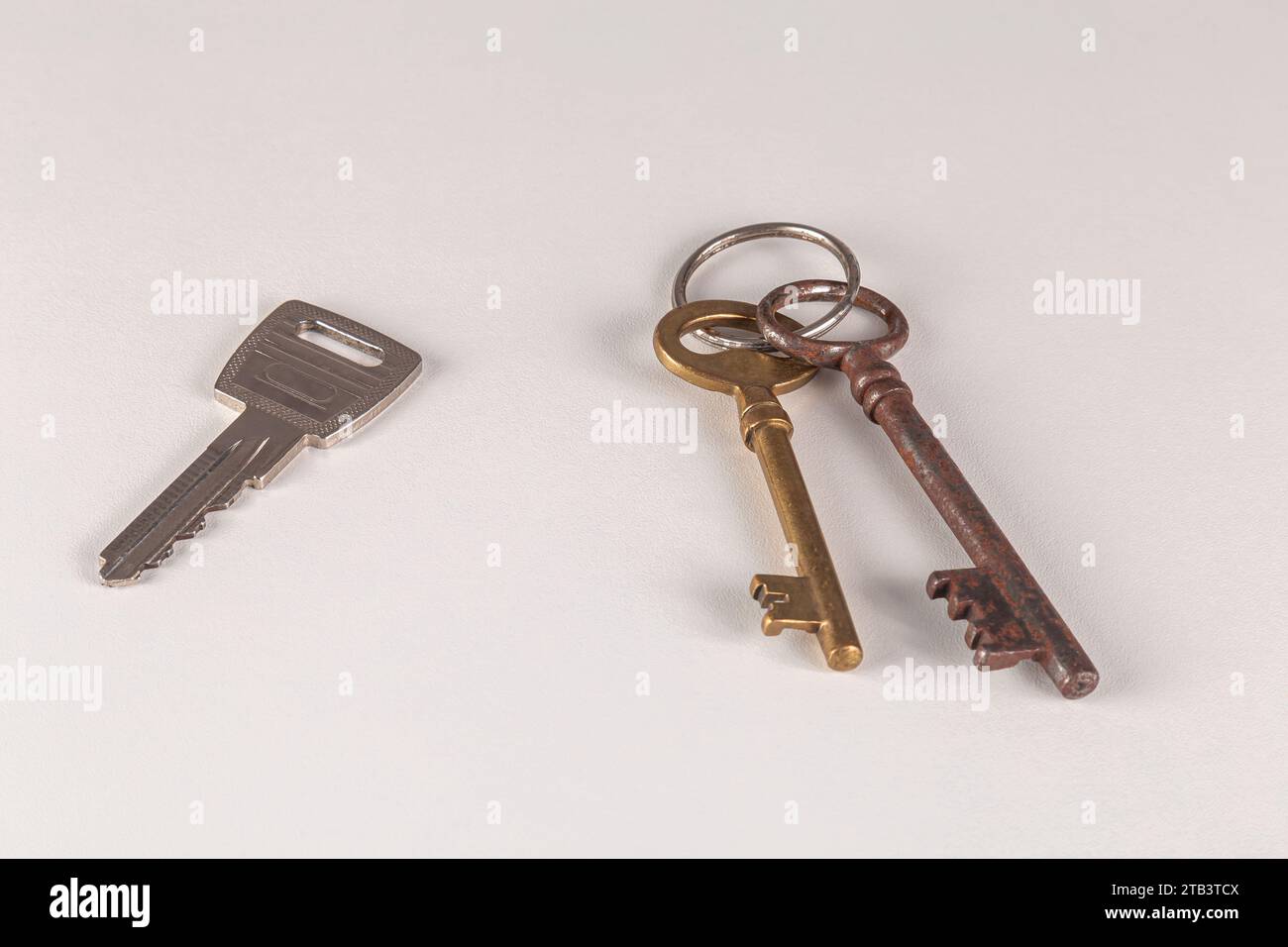 Zwei alte und ein neuer Schlüssel auf weißer Oberfläche. Nahaufnahme. Stockfoto