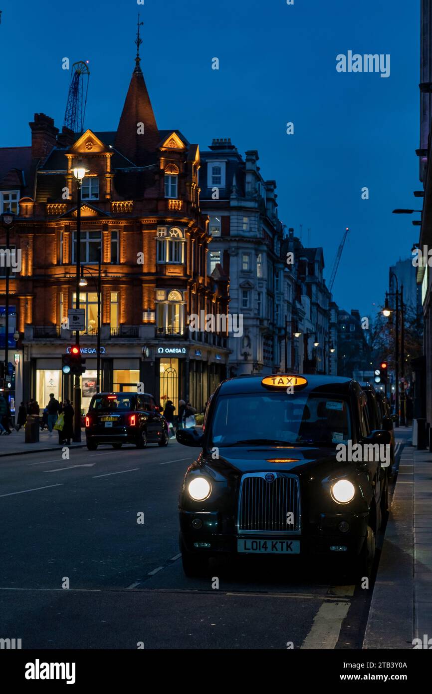 Ein schwarzes Taxi in der Londoner Innenstadt bei Nacht Stockfoto