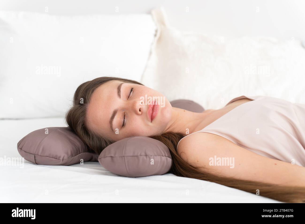 Weißes Mädchen 20-25 Jahre alt in Seidenwäsche schläft auf einem Schönheitskissen auf dem Bett im Schlafzimmer Stockfoto