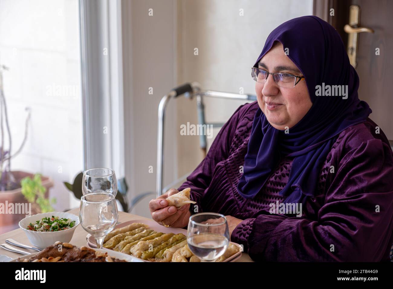 Porträt für muslimische Frau mittleren Alters auf dem Esstisch mit einem Lächeln im Gesicht Stockfoto