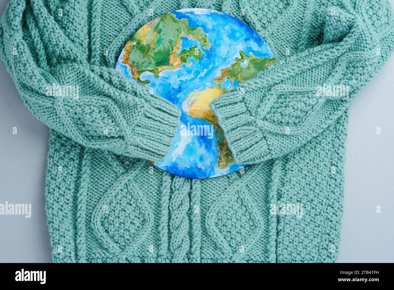 Ärmel aus Strickpullover umarmen den Planeten. Kleidung für verantwortungsbewussten Konsum. Umweltfreundlichkeit und nachhaltige Mode Stockfoto