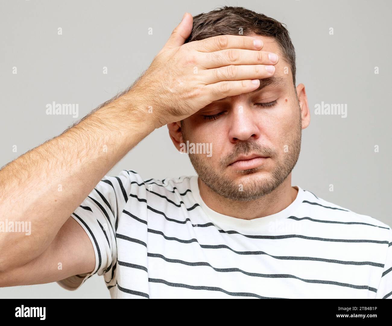 Porträt eines Mannes, der sich unwohl fühlt. Kopfschmerzen und Fieber. Der Mann berührt seine Stirn mit der Hand. Stockfoto
