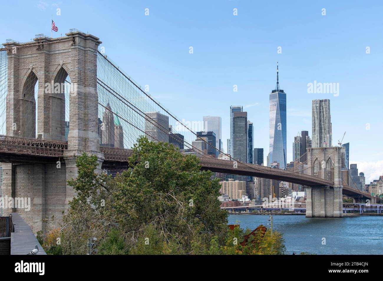 Flacher Blick vom Brooklyn Bridge Park am Wasser zur Brooklyn Bridge in Lower Manhattan, New York City, USA mit Wolkenkratzern von Lower Manhattan, Stockfoto