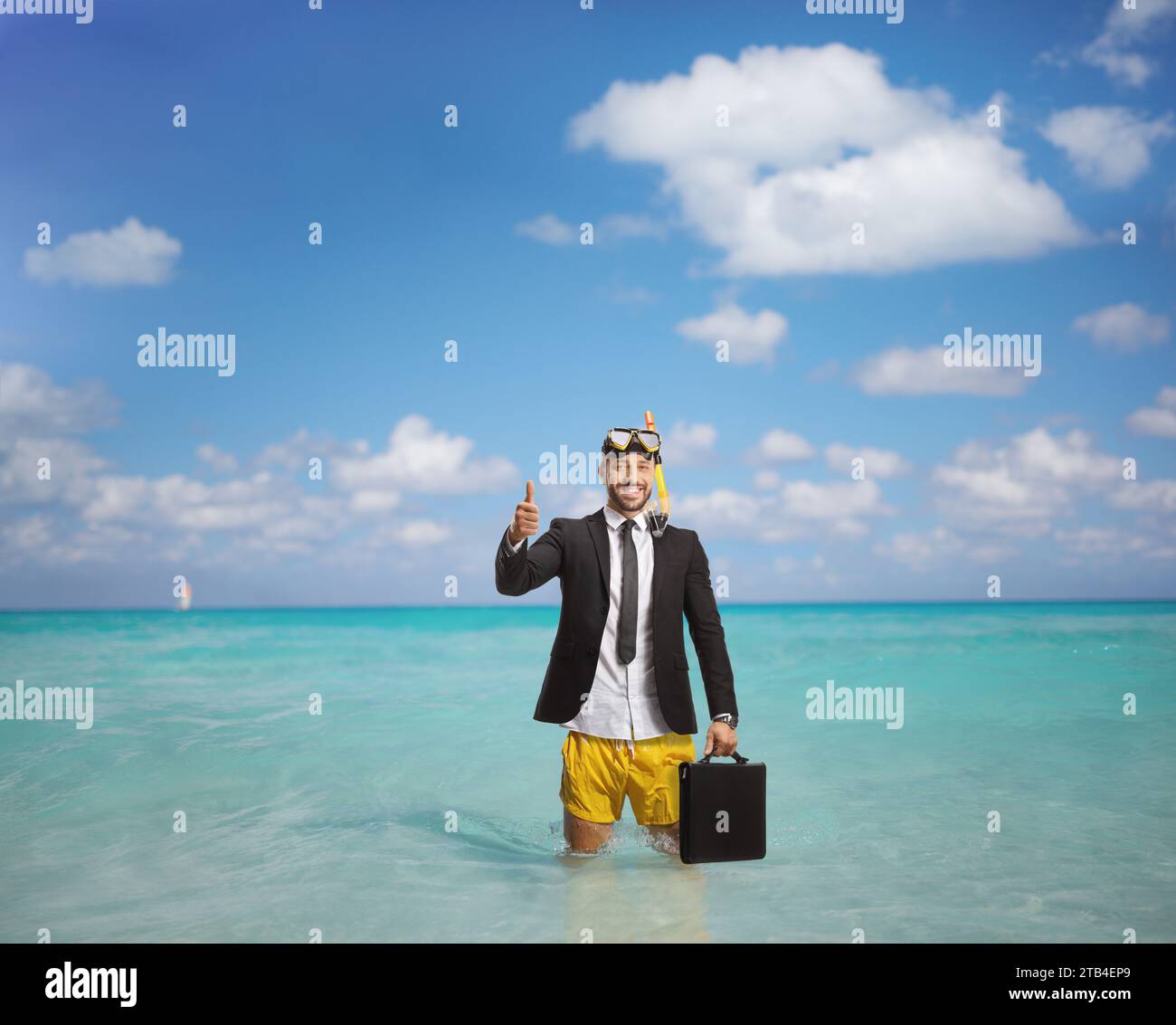 Geschäftsmann mit einer Tauchermaske im Meer, der eine Aktentasche hält und die Daumen hoch zeigt Stockfoto