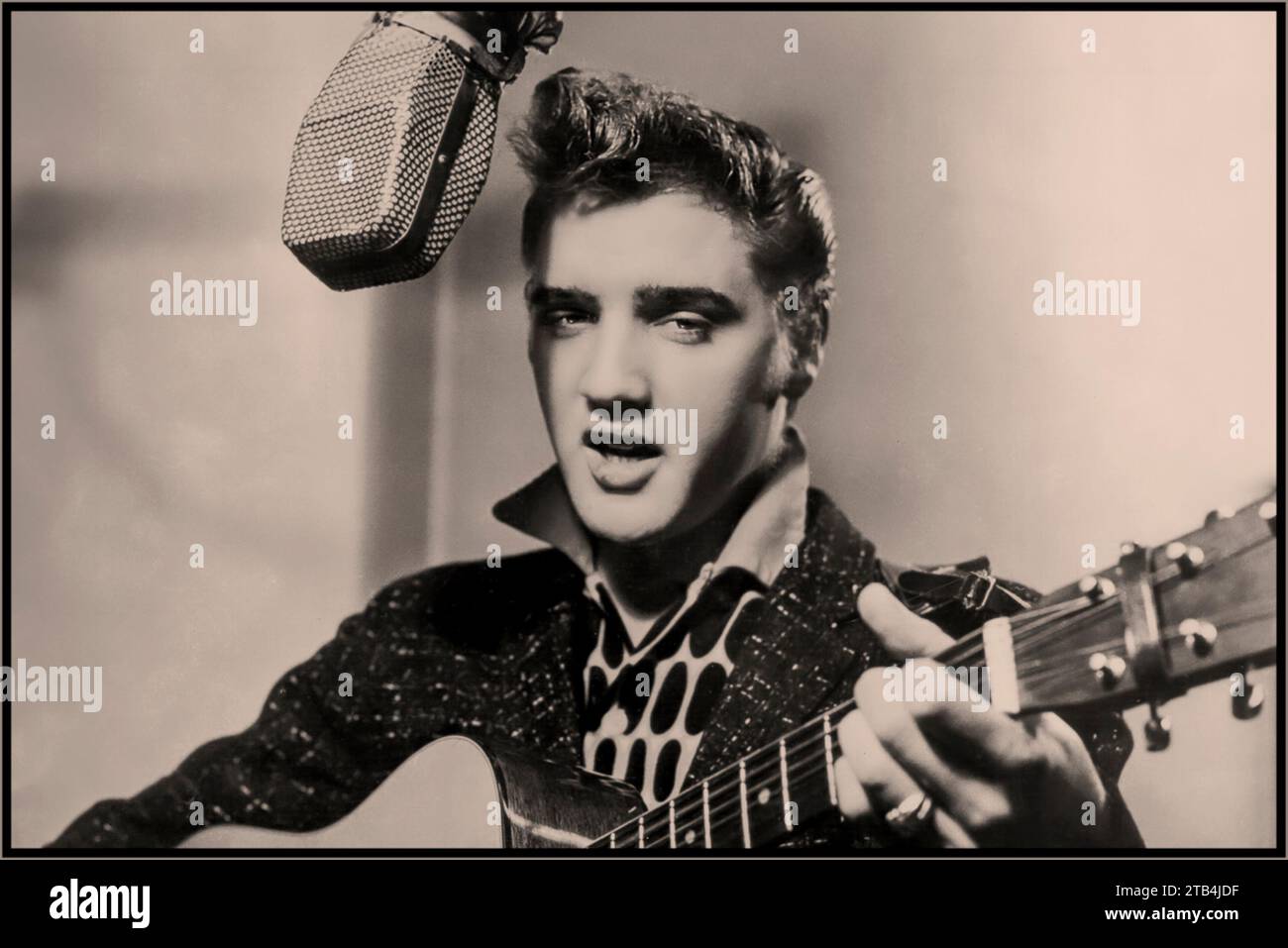 ELVIS PRESLEY ikonischer Popstar in den 1950er Jahren zu Beginn seiner Karriere, sang und spielte seine Gitarre in einem RCA Victor Aufnahmestudio mit Mikrofon der Ära. Hollywood USA 1955 Stockfoto