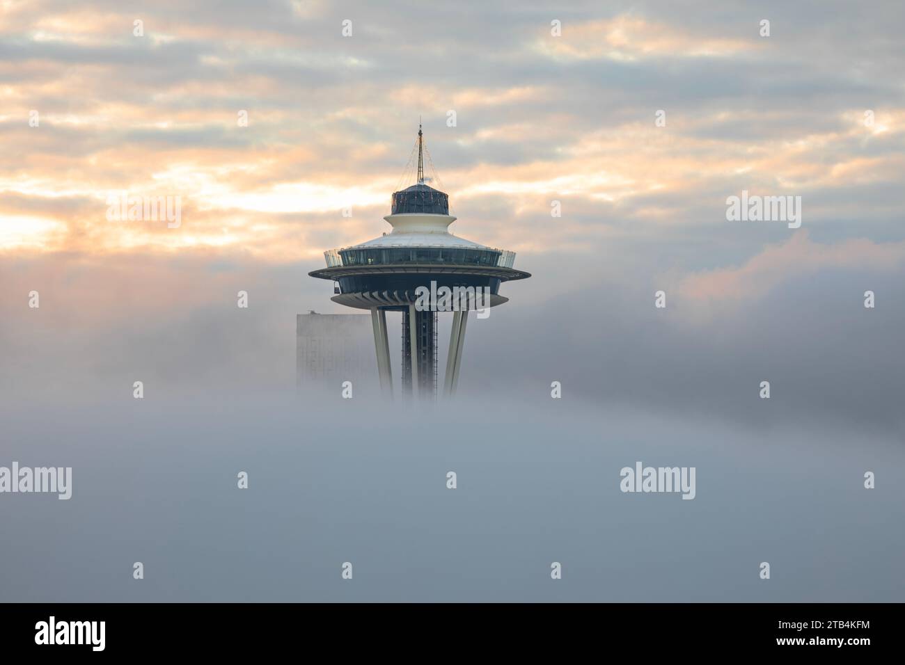 WA23869-00...WASHINGTON - aufsteigender Nebel bei Sonnenaufgang umhüllt die Space Needle und ein Hochhaus, das sich über dem Nebel erhebt. Stockfoto