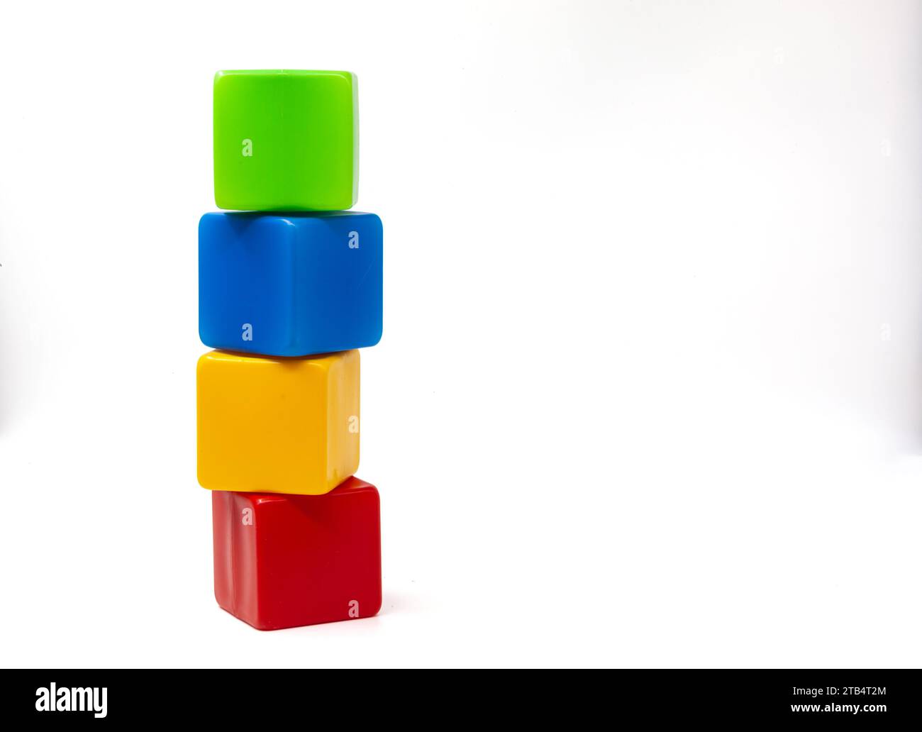 Mehrfarbige Plastikwürfel für Kinderspiele. Gelb und blau mit grünen Würfeln stehen oben auf Rot. Die Würfel sind mit einem Turm versehen. Eins auf eins. Stockfoto