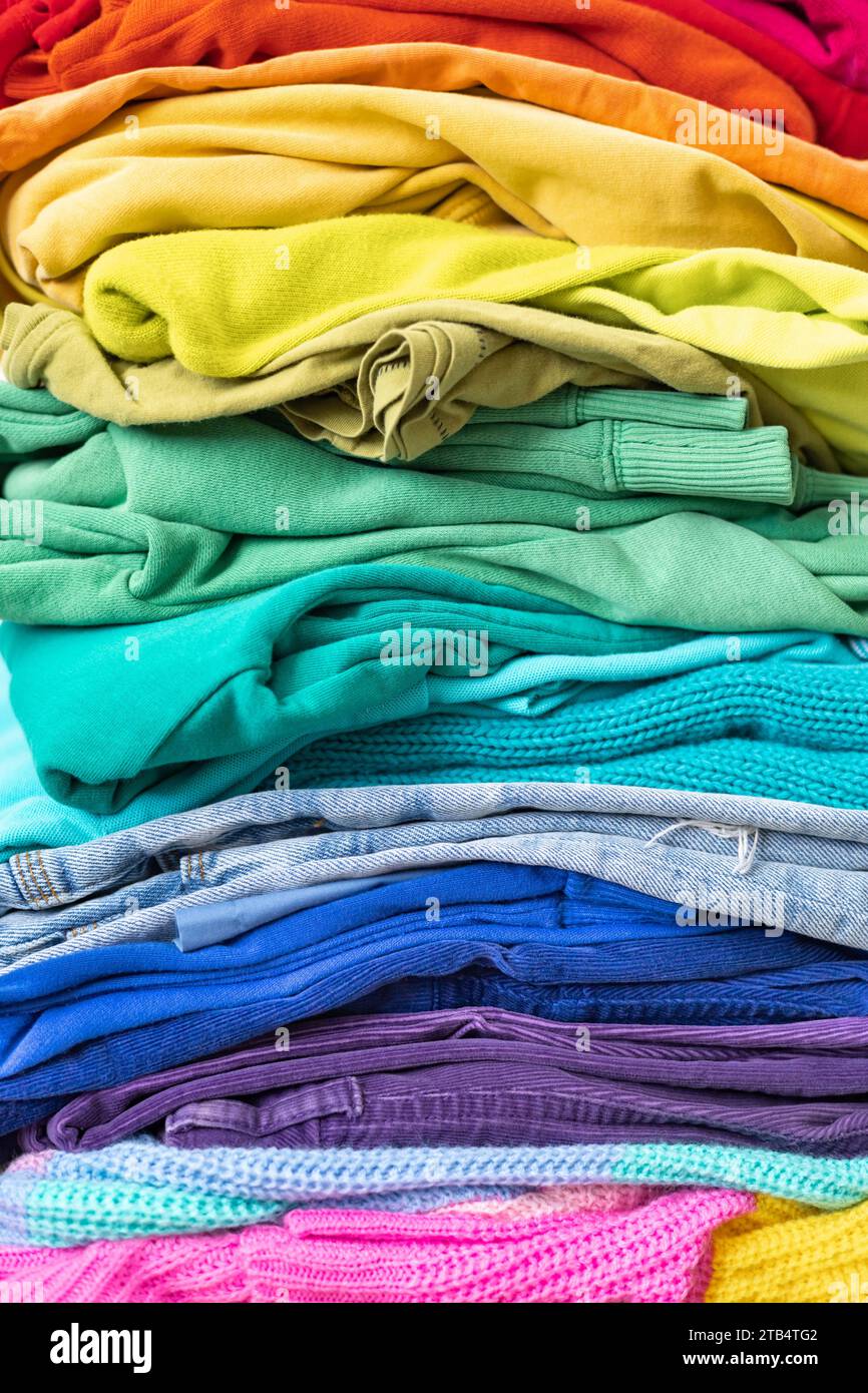 Ein Stapel Kleidung in verschiedenen Farben. Der Begriff des bewussten Bekleidungskonsums. Stockfoto