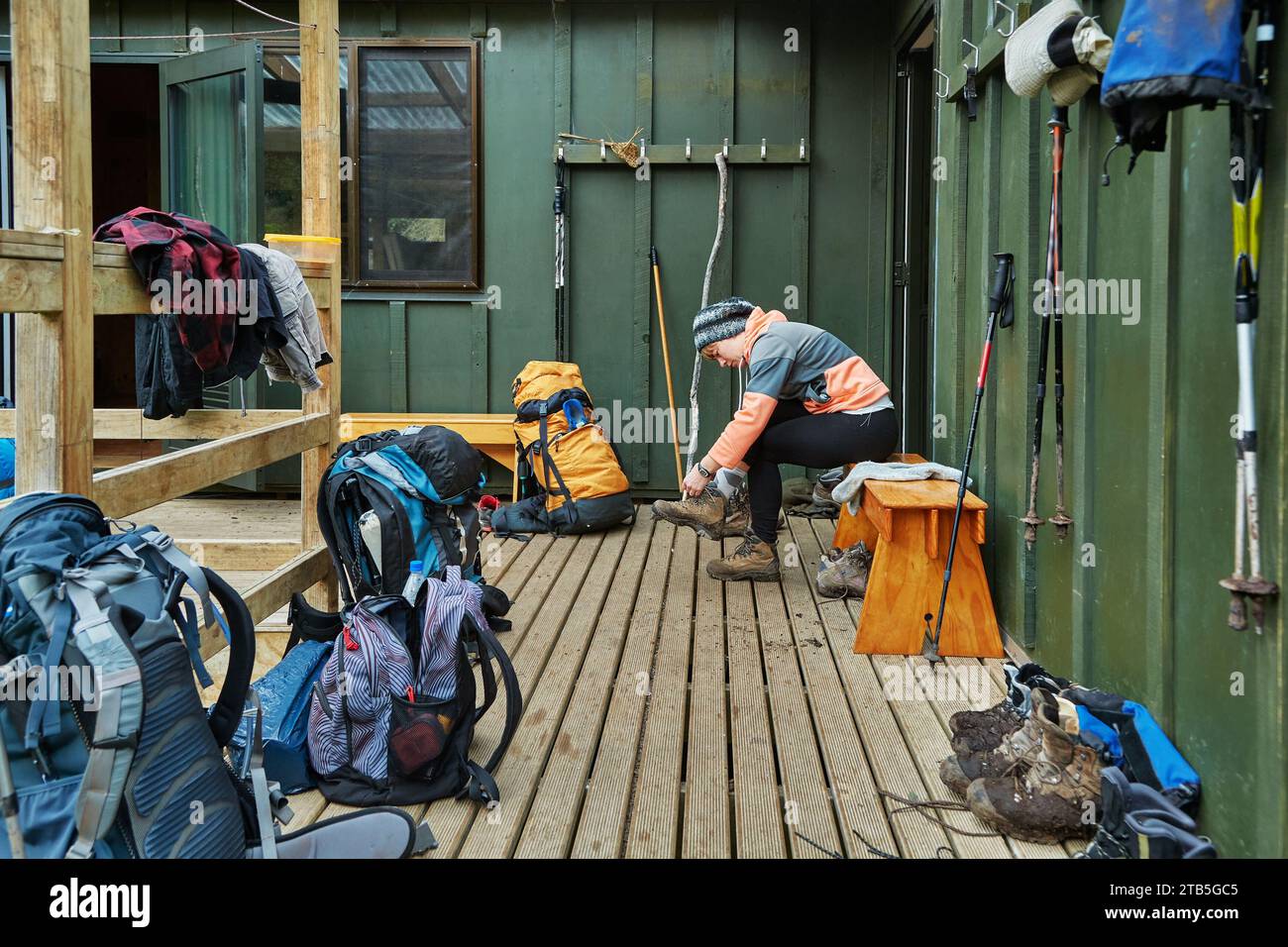 Frau, die Wanderschuhe vor einer Holzhütte auf einem Weg anzieht Stockfoto