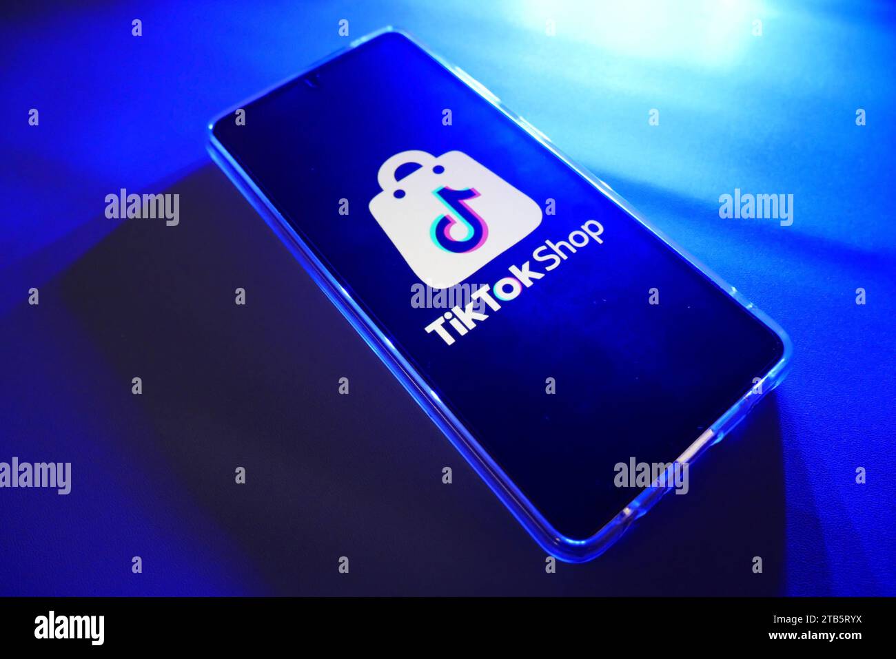 Ein Smartphone mit TikTok Shop Logo auf dem Bildschirm mit blauem Hintergrund. Ähnliches Bild in meinem Portfolio. Stockfoto