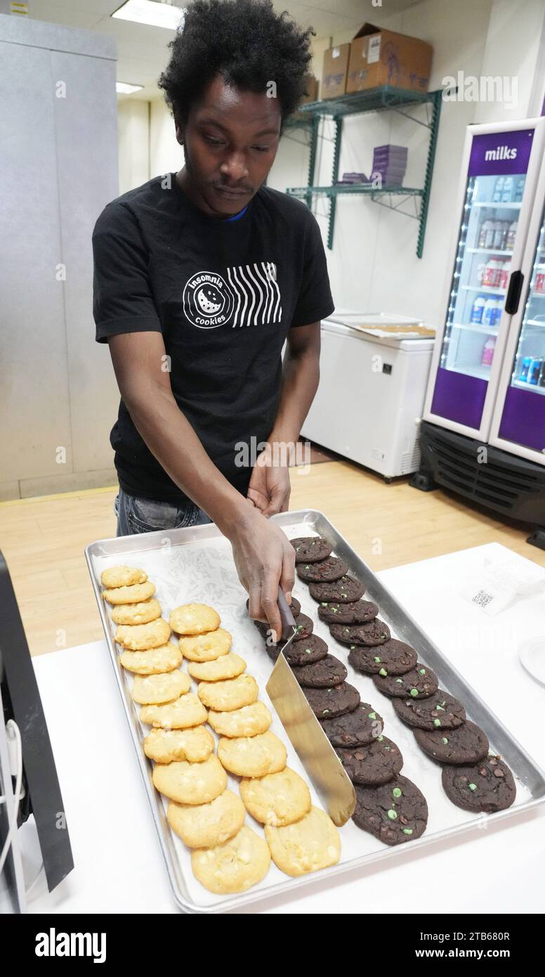 University City, Usa. Dezember 2023. Manager Trevion Henderson arrangiert am Montag, den 4. Dezember 2023, frische Cookies in einer Vitrine im Insomnia Cookies on National Cookie Day in University City, MO. Foto: Bill Greenblatt/UPI Credit: UPI/Alamy Live News Stockfoto