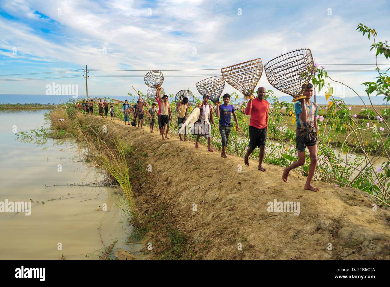 Ländliche Menschen, die mit Bambusfischfallen und -Netzen bewaffnet sind, nehmen an der Feier eines 200-jährigen Winterfischfestivals im Jofra Beel of gasbari union of Kanaighat upazila in Sylhet, Bangladesch, Teil. Stockfoto