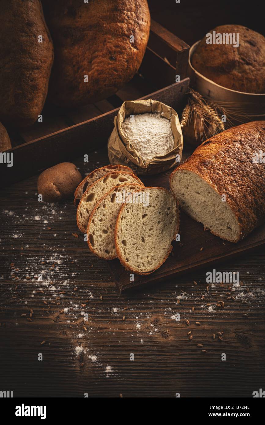 Handwerklich geschnittene Brotlaibe auf dunklem Holzhintergrund Stockfoto