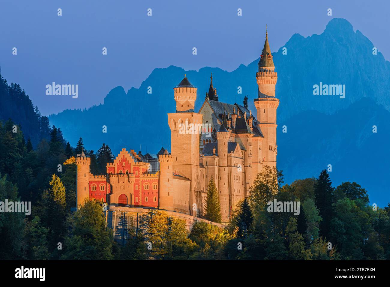 Schloss Neuschwanstein, beleuchtet nach Sonnenuntergang, umgeben von Herbstfarben. Das Schloss befindet sich in der Nähe der Stadt Füssen im Allgäu in Bayern Stockfoto