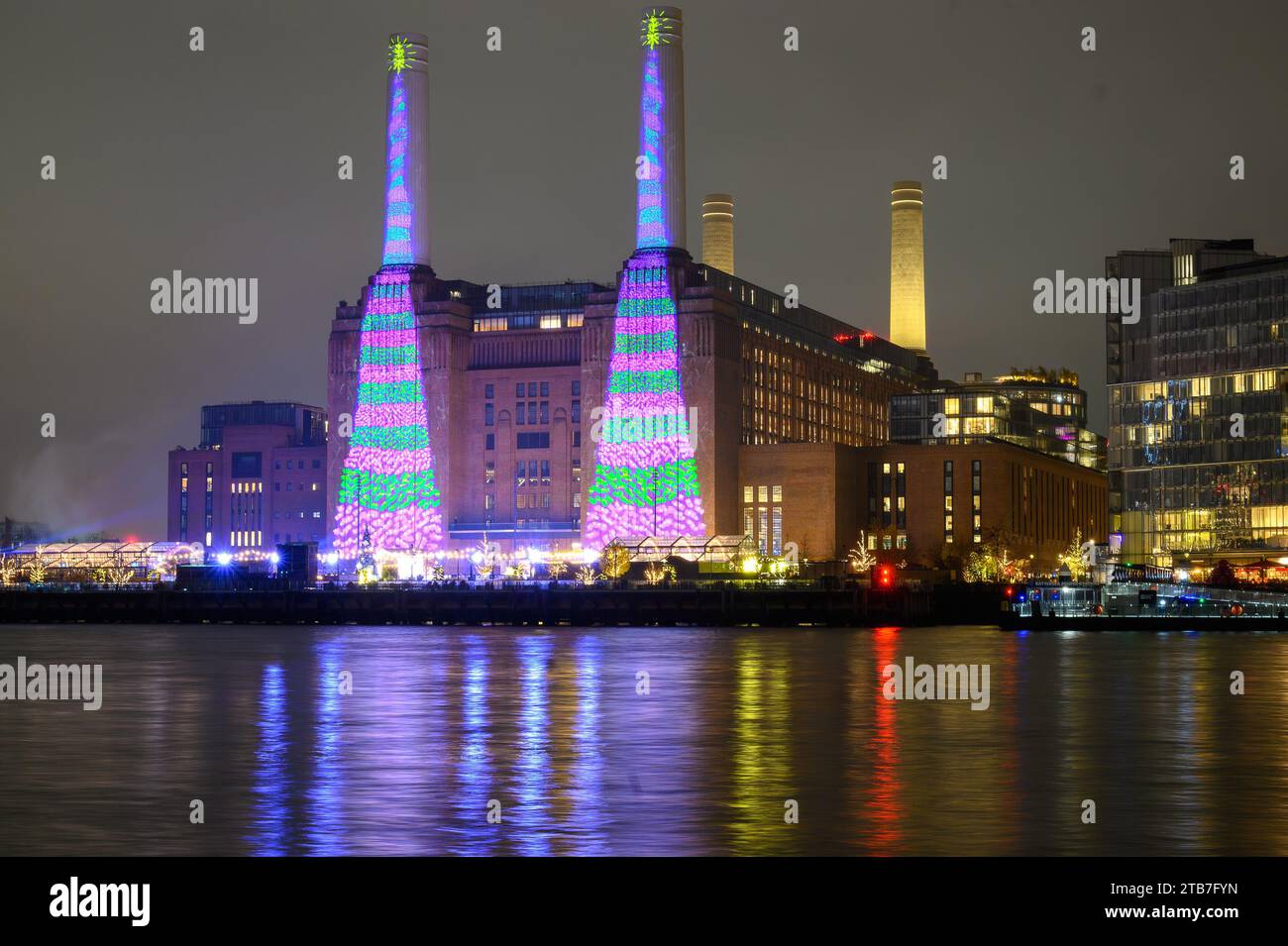 London, Großbritannien. Dezember 2023. Mit einem ipad hat David Hockney zwei große, grün und violett gestreifte Weihnachtsbäume geschaffen, von denen jeder einen goldenen Stern an der Spitze hat. Die zwei 100 Meter hohen Schornsteine mit Blick auf die Themse sind auf den Kraftwerken zu sehen. Das Weihnachtskunstwerk soll den Menschen in London, Großbritannien, „Freude und Hoffnung“ bringen. Credit: Mary-Lu Bakker/Alamy Live News Credit: Mary-Lu Bakker/Alamy Live News Stockfoto