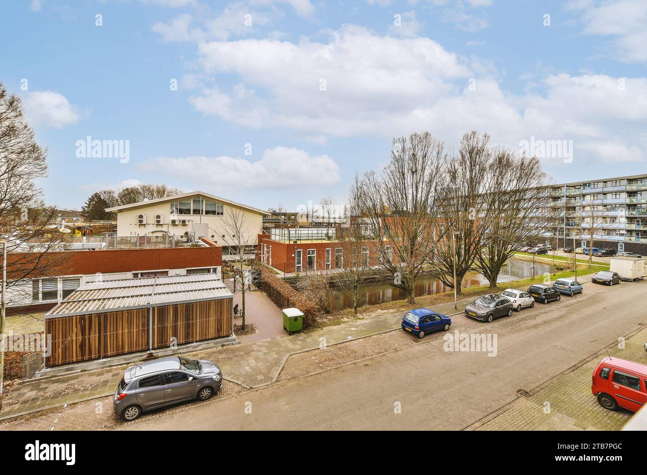 Luftaufnahme von Wohngebäuden mit Autos, die tagsüber auf der Straße in der Stadt geparkt sind, bei bewölktem Himmel Stockfoto