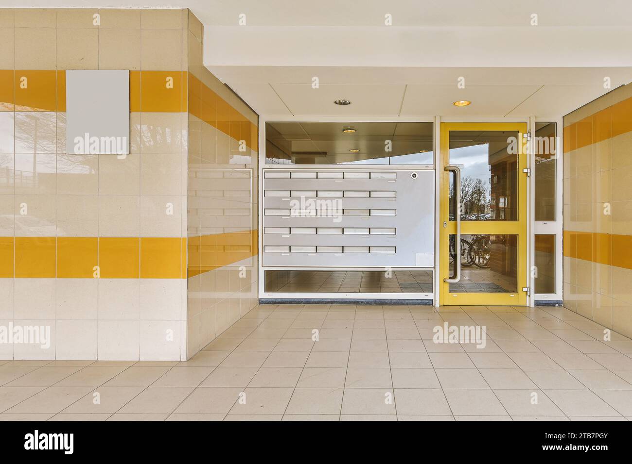 Äußere des modernen Gebäudes mit großem Fenster und gelber Eingangstür, tagsüber auf gefliestem Boden Stockfoto