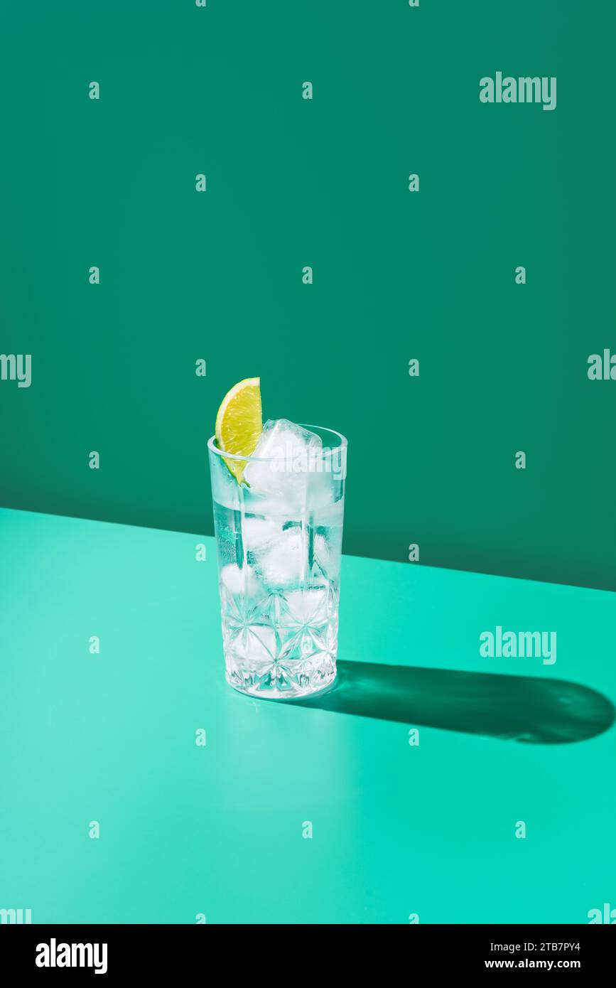Ein mit Gin Tonic gefülltes Glas mit einer Limettenscheibe steht vor ...