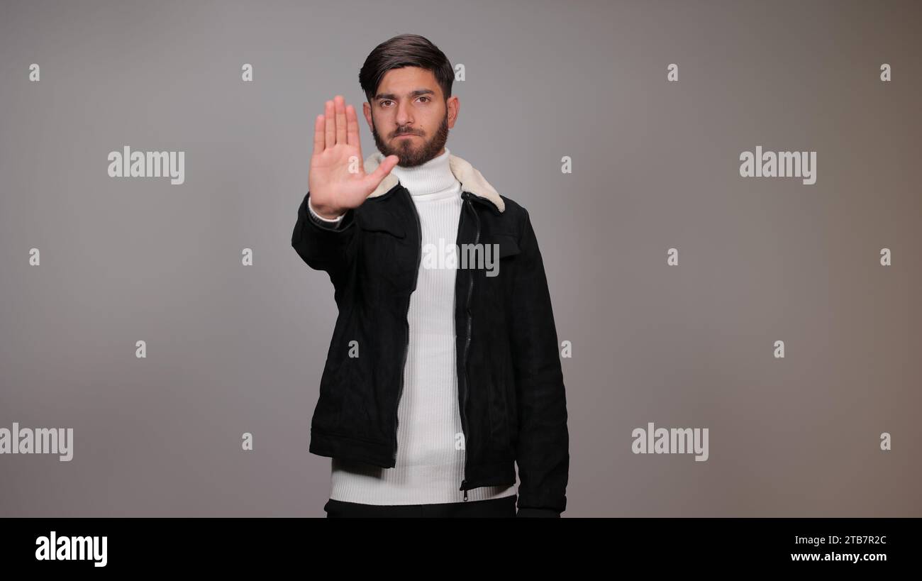 Ein junger Mann, der seine Hand zur Kamera hält, signalisiert das Konzept des „Stopp“ | Ein junger Mann, der der Kamera eine „Stopp“-Geste zeigt. Stockfoto