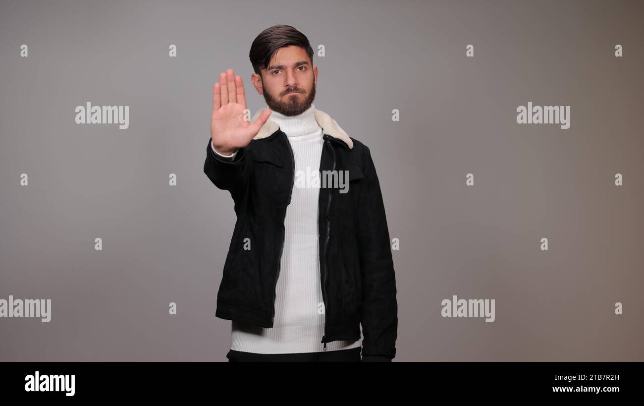 Ein junger Mann, der seine Hand zur Kamera hält, signalisiert das Konzept des „Stopp“ | Ein junger Mann, der der Kamera eine „Stopp“-Geste zeigt. Stockfoto