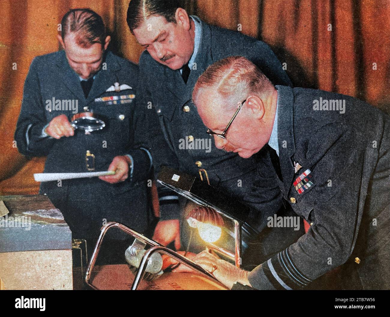 BOMBERKOMMANDO - der RAF Bomber Command Commanding Officer Arthur Harris untersucht ein Aufklärungsfoto neben seinem Stellvertreter Robert Saundby im November 1942 mit Air Vice-Marshal Ronald Graham auf der linken Seite Stockfoto