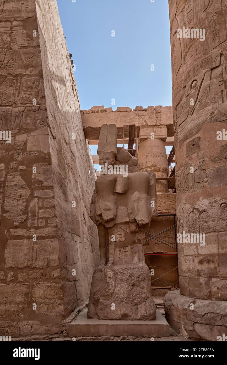 Der Eingang zu einem antiken Tempel wird vom Sonnenlicht beleuchtet, während eine Steinskulptur mit antiken Schriften im Vordergrund steht Stockfoto