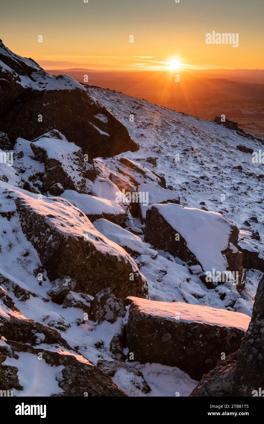 Sonnenuntergang über schneebedeckten Felsen am Sourton Tor, Dartmoor National Park, Devon, England. Winter (Dezember) 2022. Stockfoto