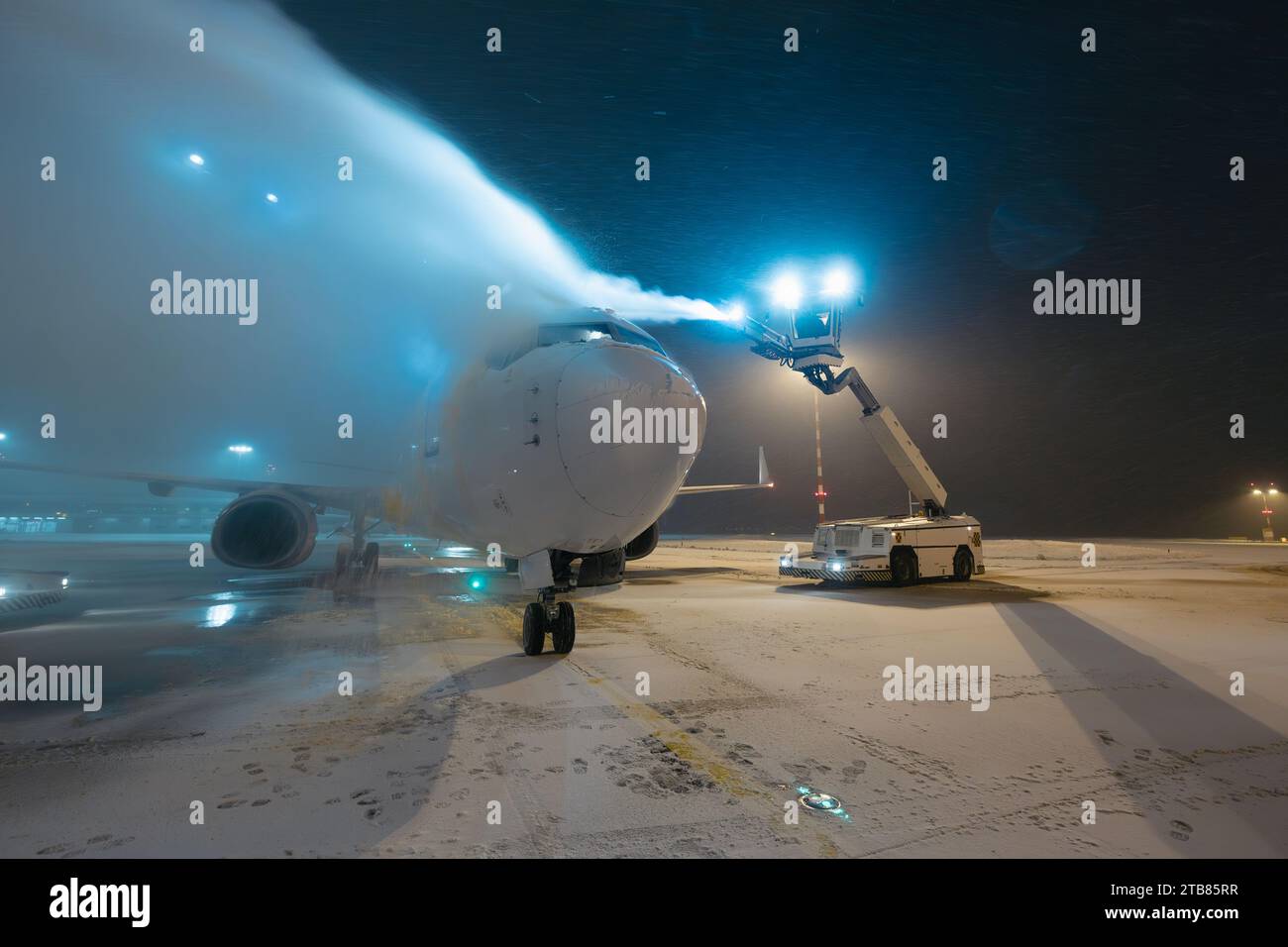 Enteisung des Flugzeugs vor dem Flug. Winter frostige Nacht- und Bodenservice am Flughafen bei Schneefall. Stockfoto