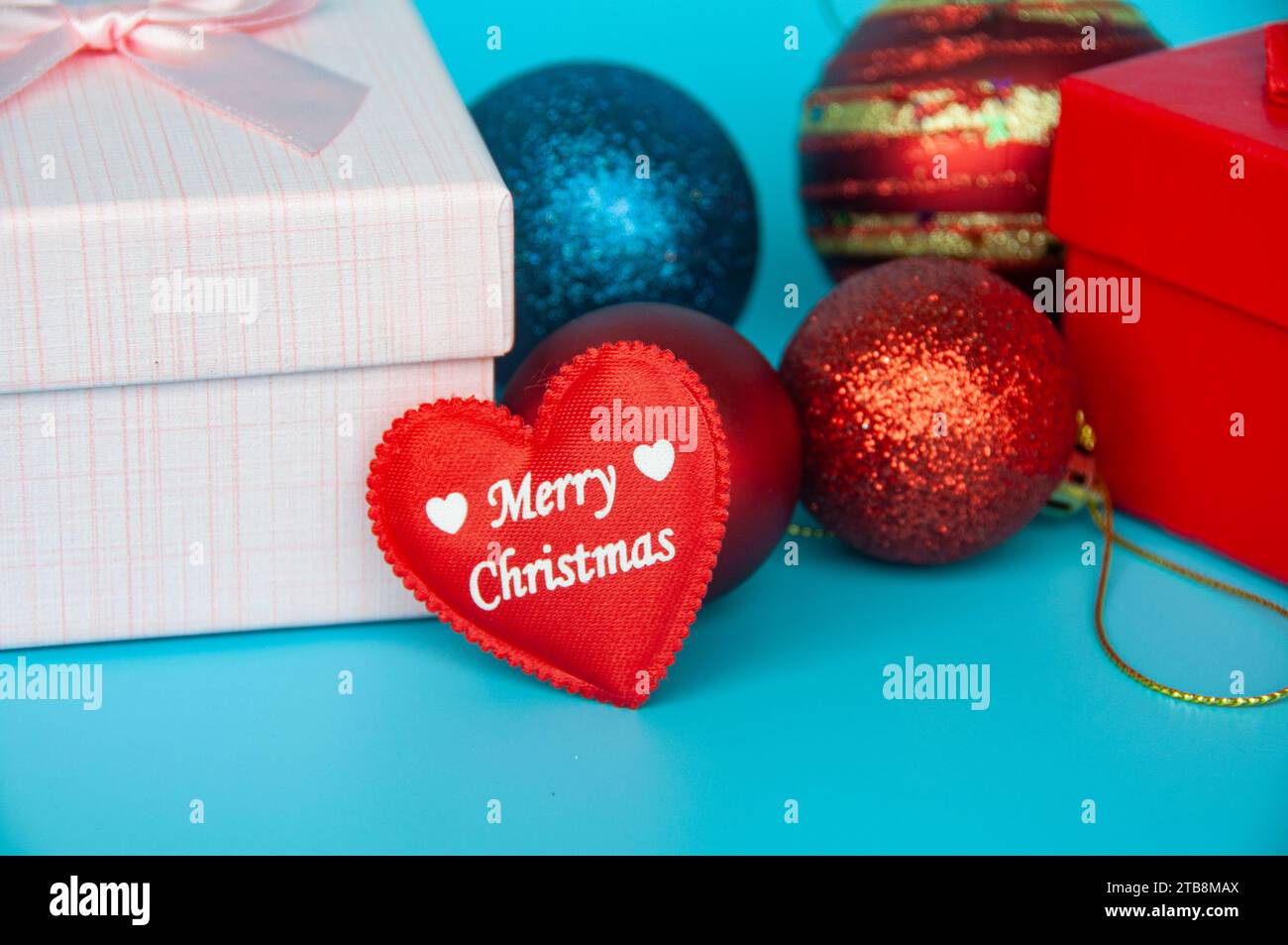 Fröhlicher Weihnachtstext in Herzform mit Weihnachtsgeschenken und -Dekoration. Stockfoto