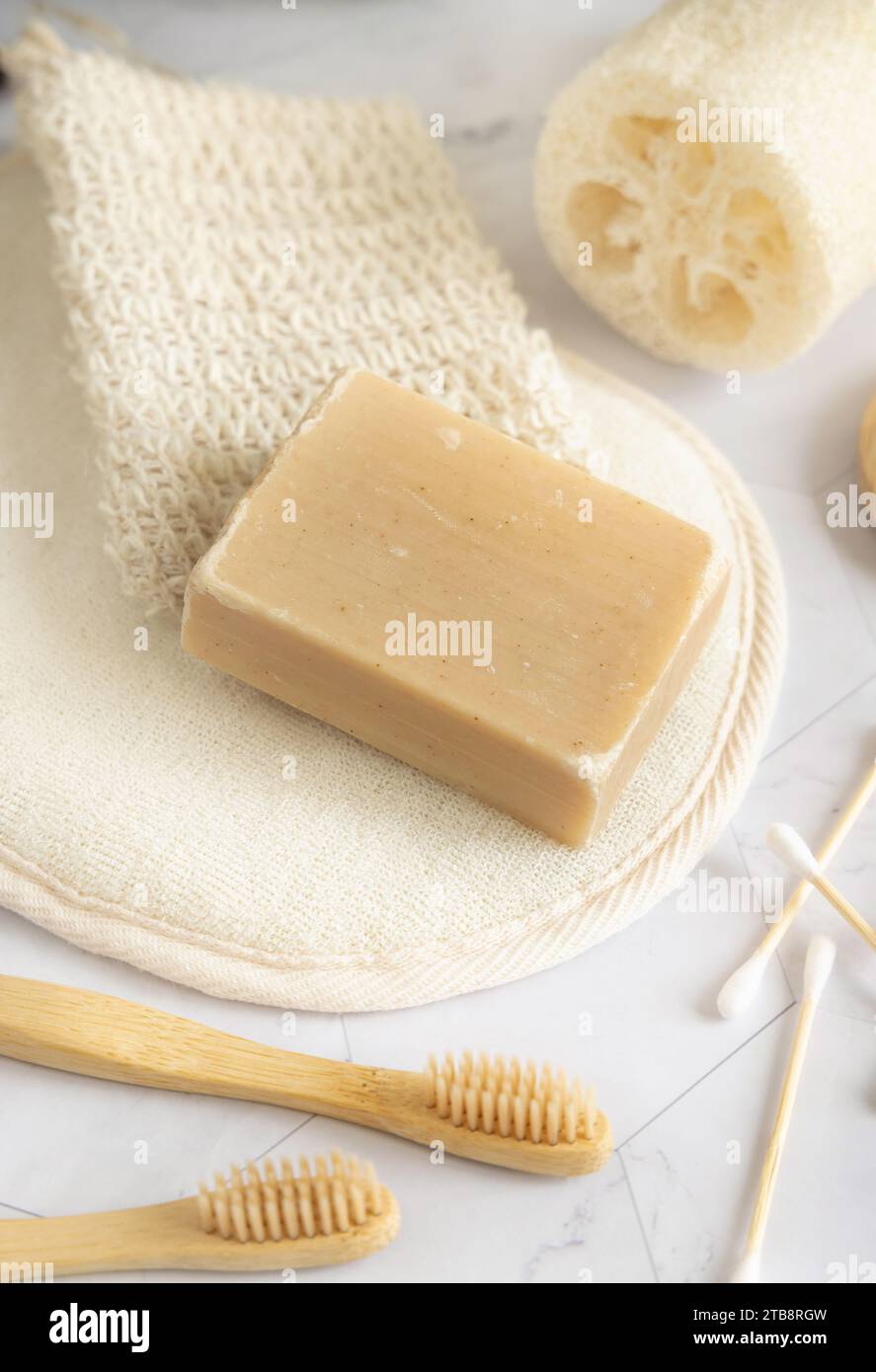 Bio handgemachte beige Seifenstange auf Seifenspartasche in der Nähe von Hygieneartikeln - Luffa Schwamm, Bambus Zahnbürsten und Wattestäbchen aus nächster Nähe. Natürliche Kräuter PR Stockfoto