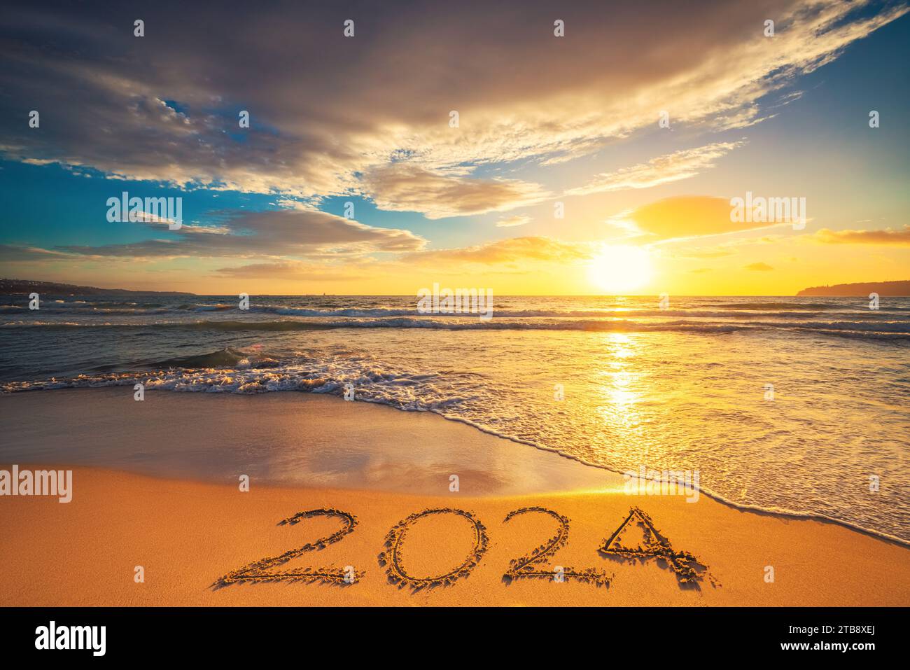 Happy New Year 2024 Konzept, Schriftzug am Strand. Geschriebener Text am Strand bei Sonnenaufgang. Stockfoto