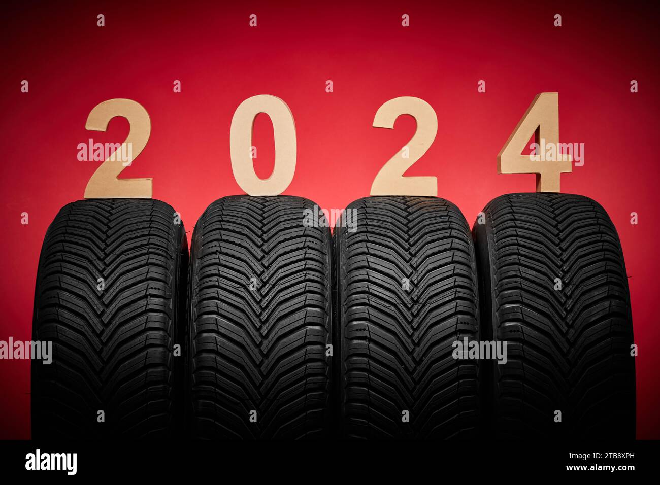 Autoreifen, Winterräder, isolierte neue Reifen, Happy New Year 2024 auf rotem Hintergrund Stockfoto