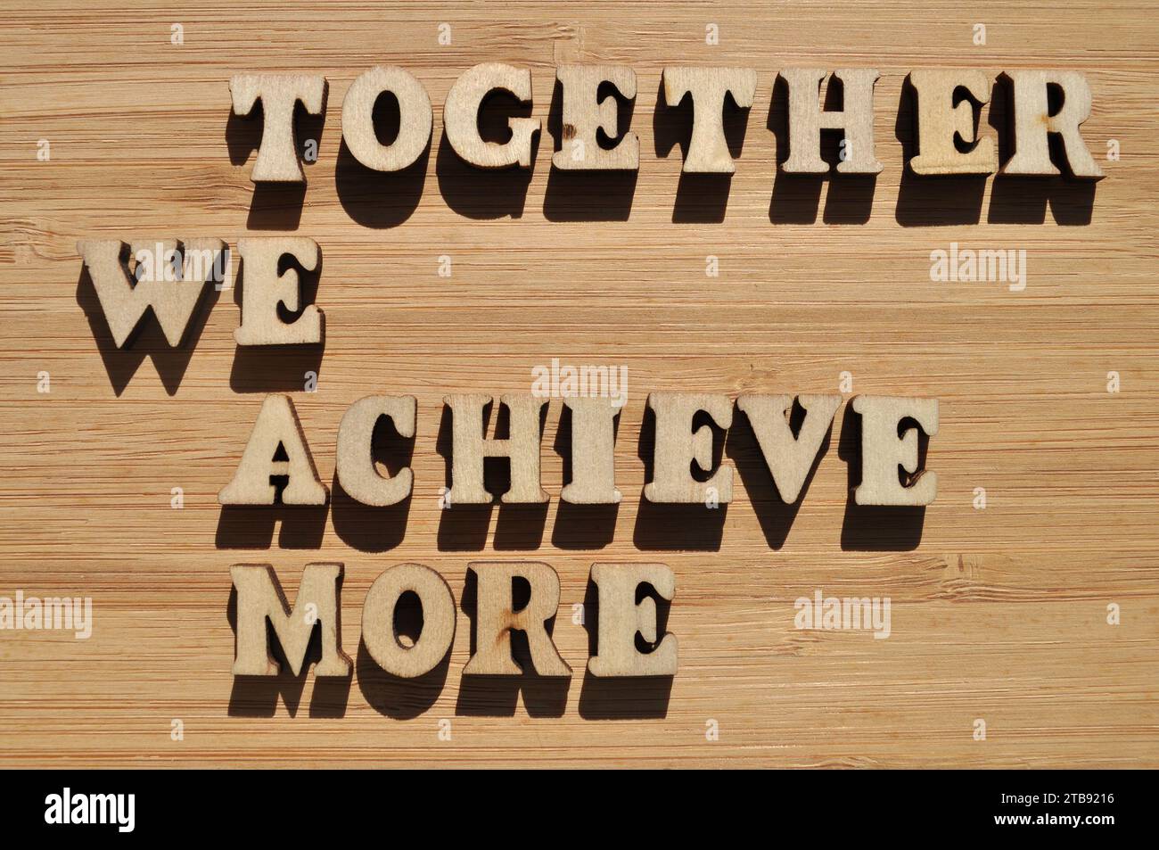 TEAM, gemeinsam erreichen wir mehr, Wörter in hölzernen Alphabeten isoliert auf Hintergrund als Bannerüberschrift Stockfoto