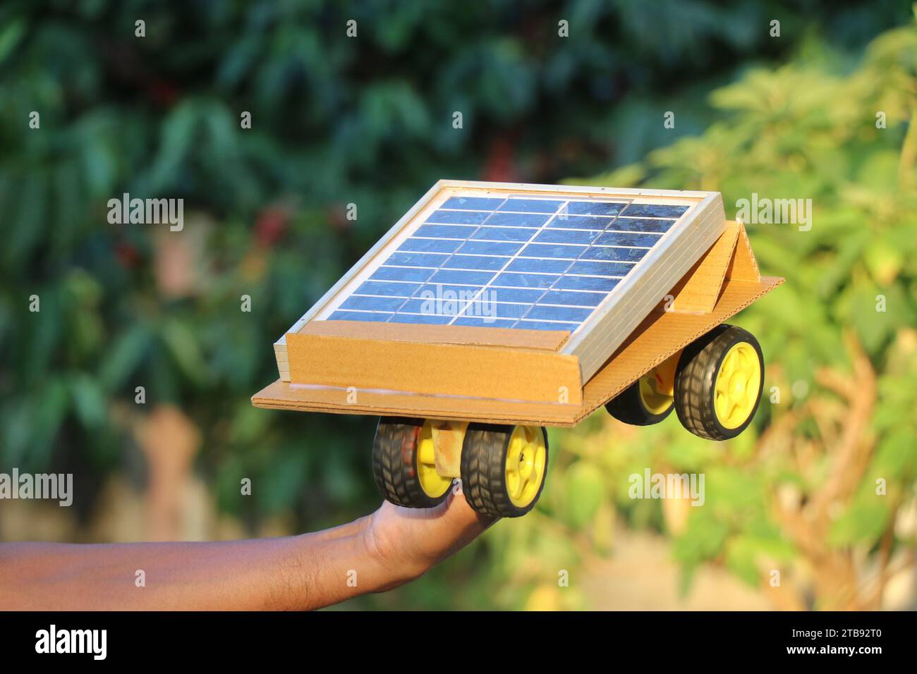 Sonne oder solarbetriebenes Auto in der Hand. Solarmodul wandelt die Energie von der Sonne um und treibt die Räder an, die mit dem Gleichstrommotor verbunden sind Stockfoto