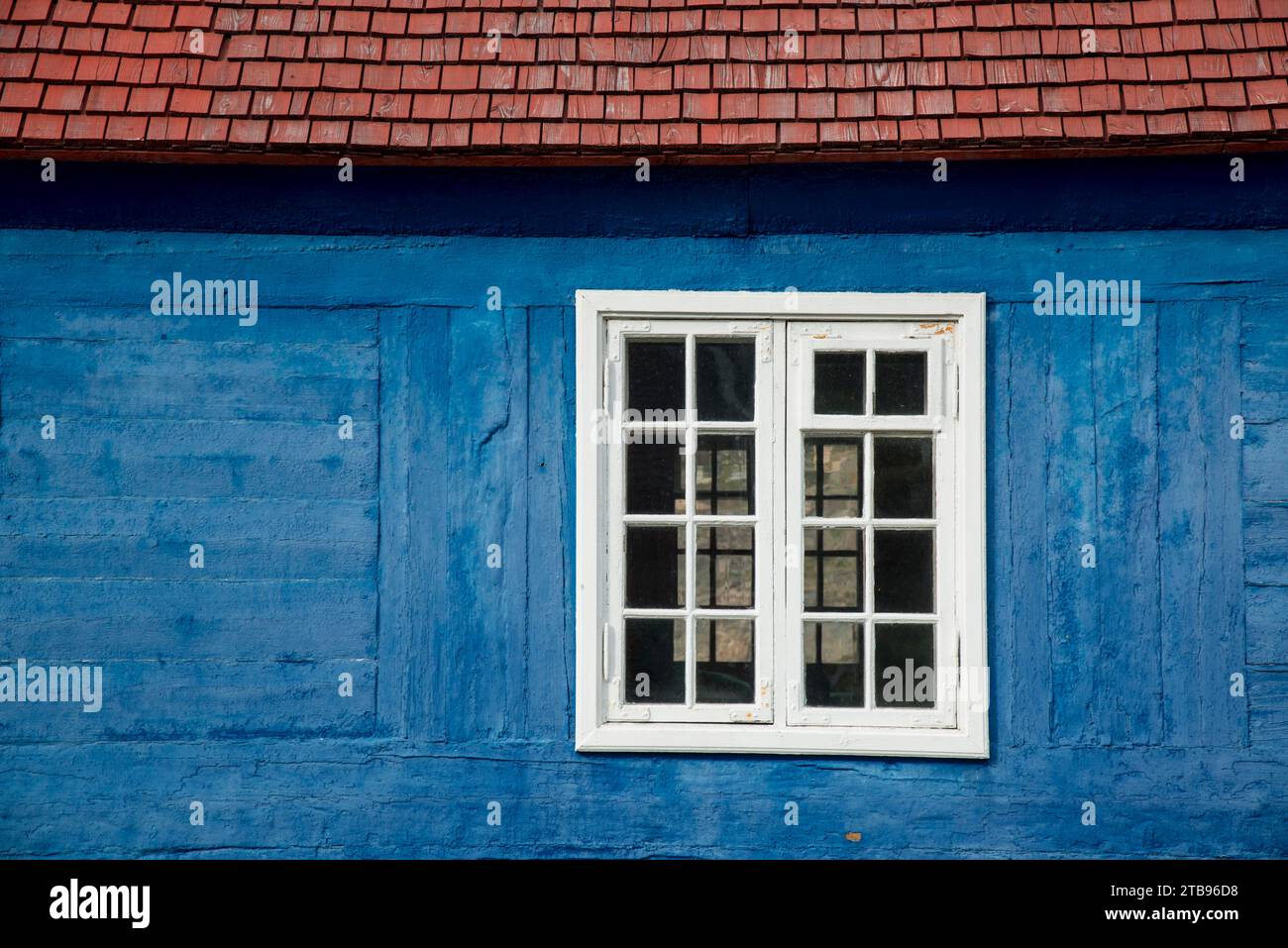 Altes Holzfenster in einem blau lackierten Blockhaus; Sisimiut, Grönland Stockfoto