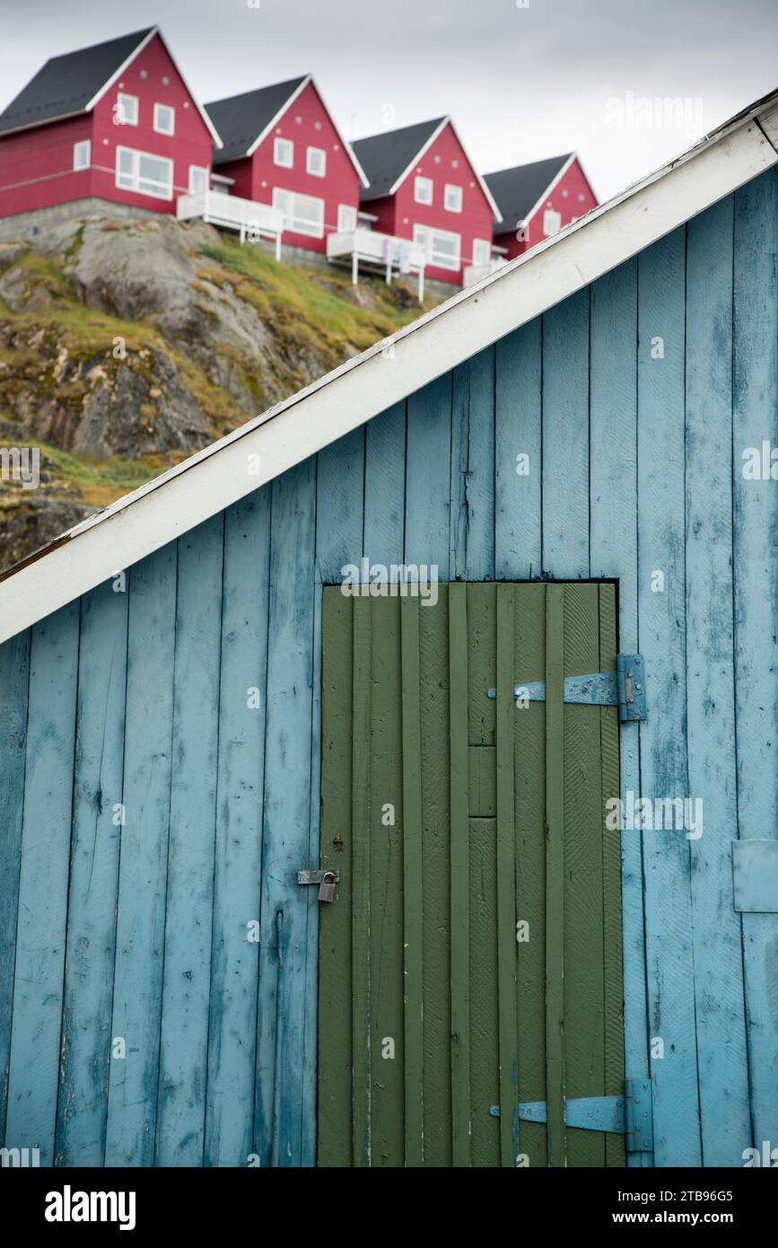 Mit einem Vorhängeschloss verschlossene Tür in einer Hütte, die von einem Wohnhaus auf einem Kamm übersehen wird; Sisimiut, Grönland Stockfoto