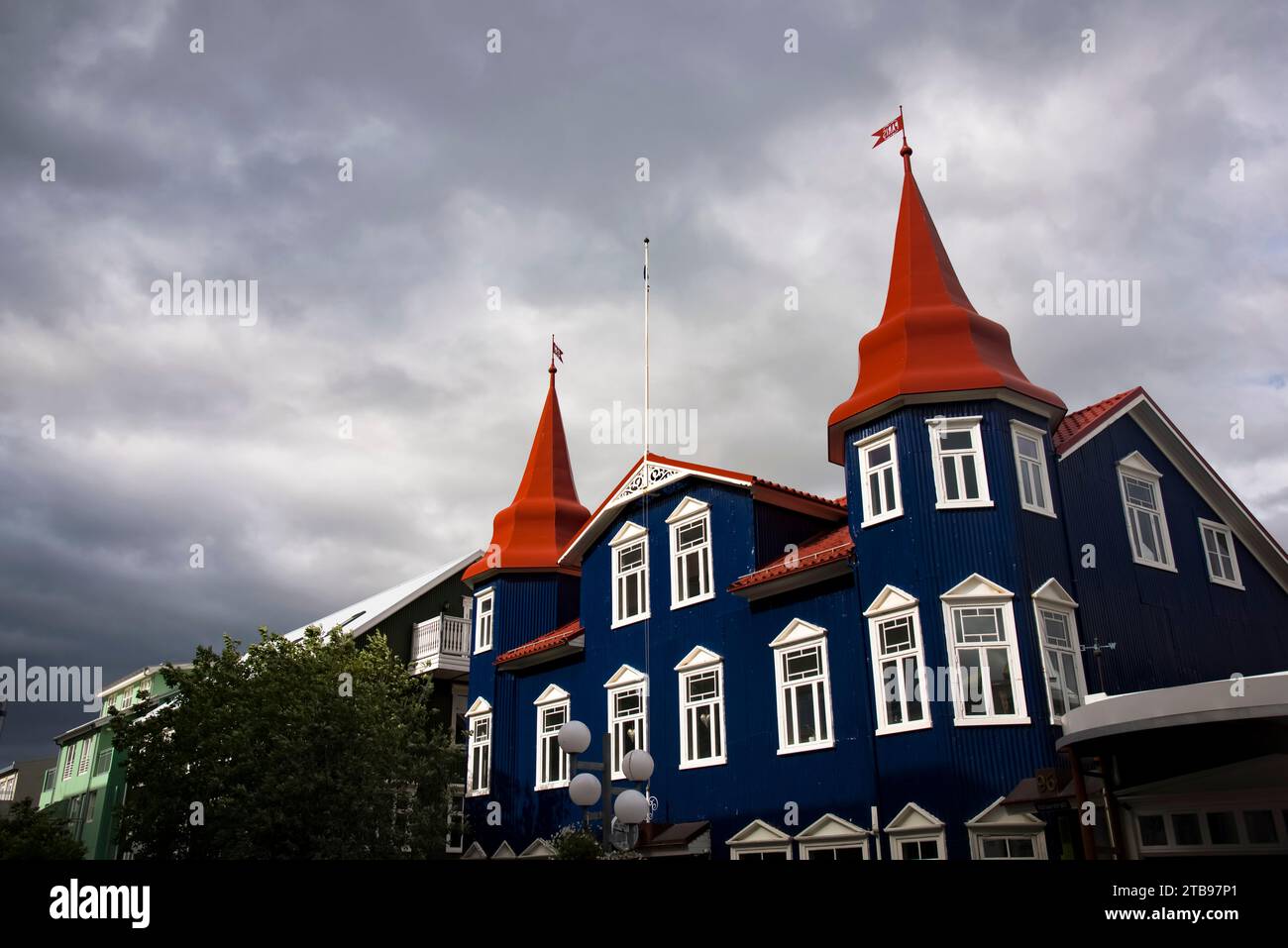 Gebäude mit dunkelblauer Fassade, weißen Fensterverkleidungen und roten Türmchen in der Hafenstadt Akureyri; Akureyri, Island Stockfoto