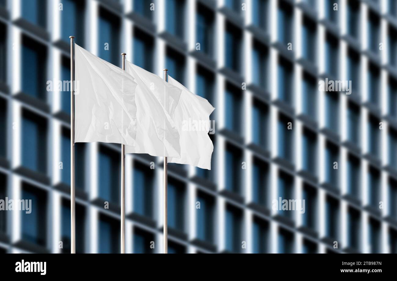 Drei weiße Firmenflaggen winken im Wind gegen verschwommenes Bürogebäude. Leeres Flag-Modell zum Hinzufügen eines Logos, Symbols oder Schildes Stockfoto