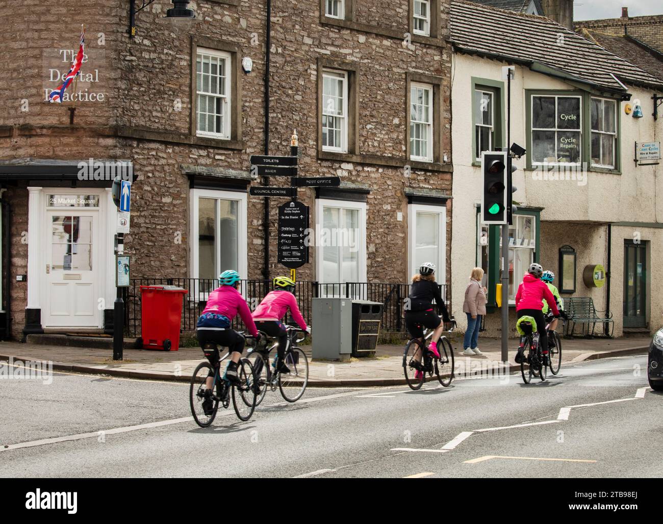 Radfahrerinnen fahren mit dem Fahrrad durch das Stadtzentrum von Kirkby Stephen, Cumbria Stockfoto