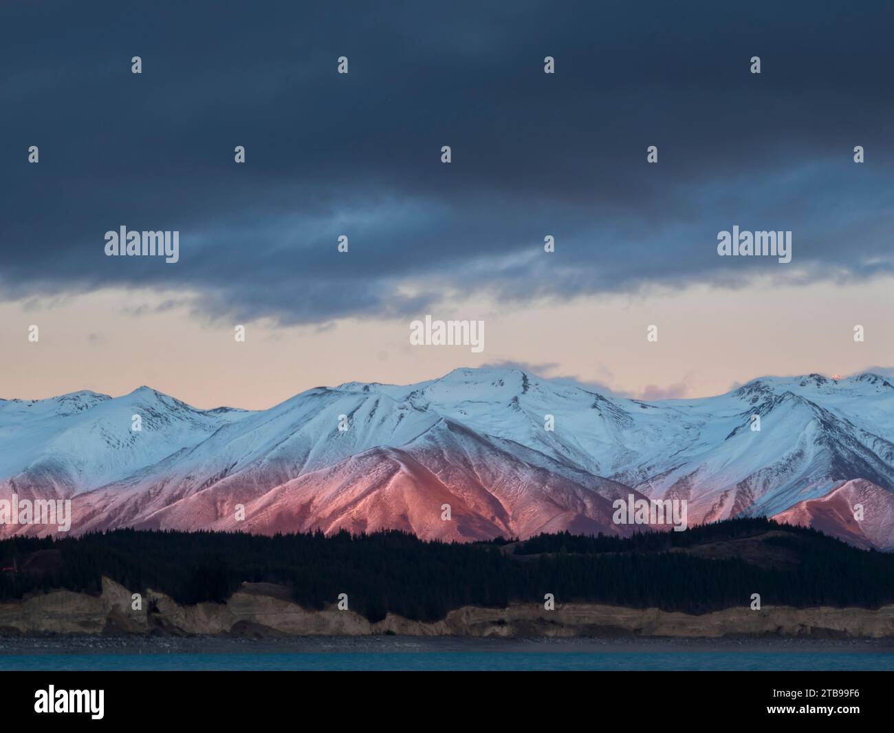 Das Morgenlicht beleuchtet die schneebedeckten Rhoboro Hills mit einem ruhigen Lake Pukaki im Vordergrund; Twizel, South Island, Neuseeland Stockfoto